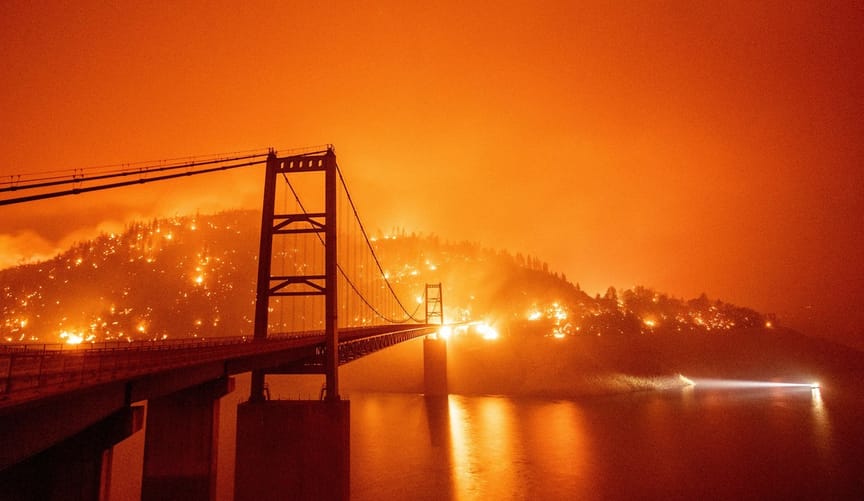 A bridge on a lake is surrounded by fire