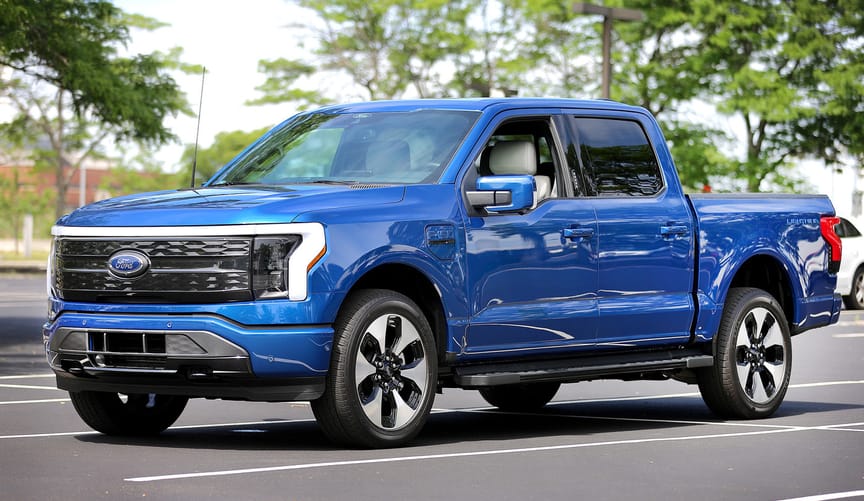 A blue ford F-150 lightning EV truck in a parking lot
