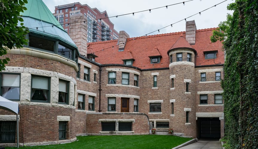 A large brick mansion surrounded by tall hedges