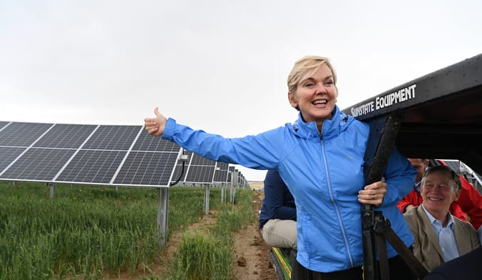 A woman in a blue jacket smiles as she tours a solar farm