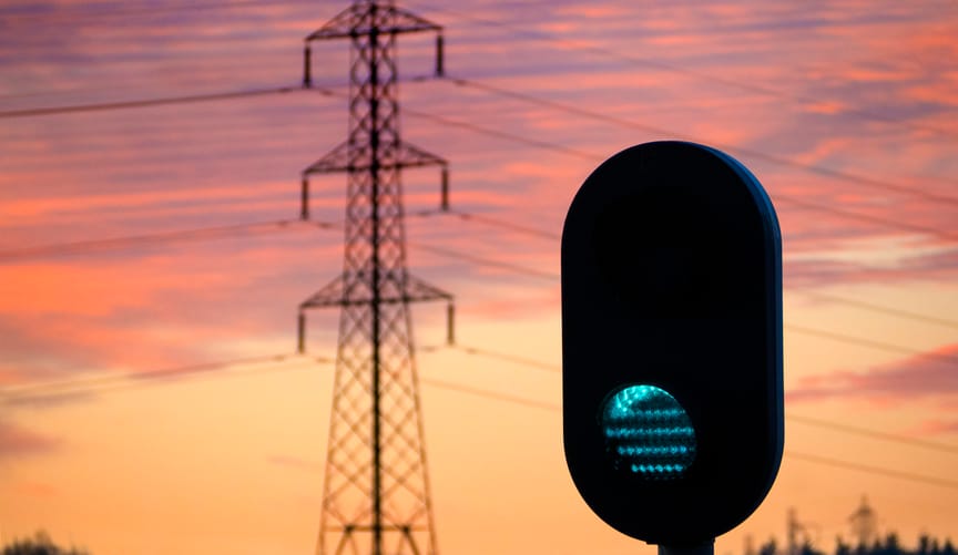 A green traffic signal with transmission lines in the background