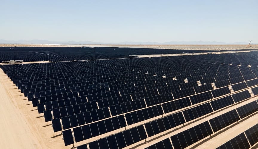 A large-scale solar project stretches as far as the eye can see at a desert site.
