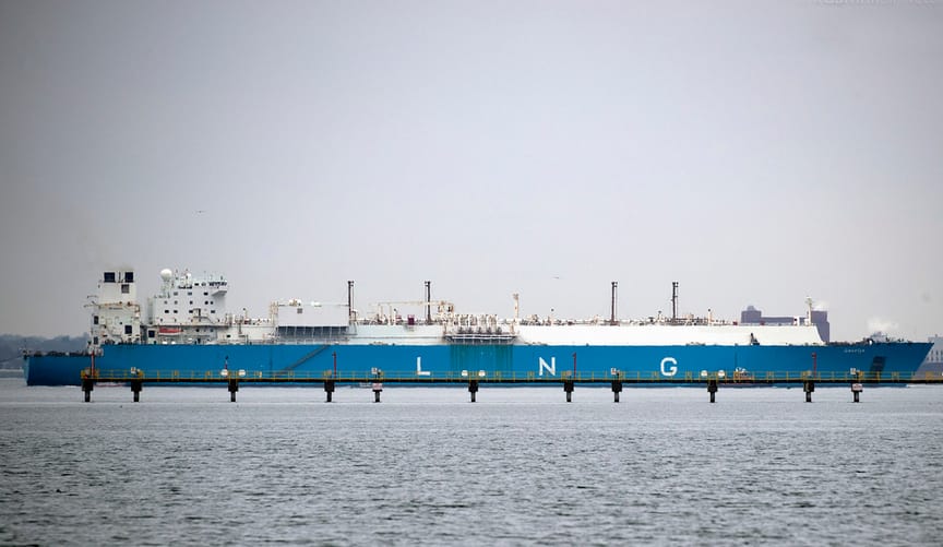 A large blue ship with the letters LNG on the side approaches a port