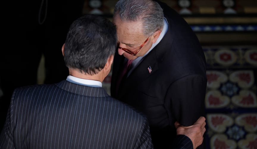 Two men in dark suits have a conversation