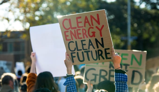 A protestor holds up a sign that says clean energy, clean future