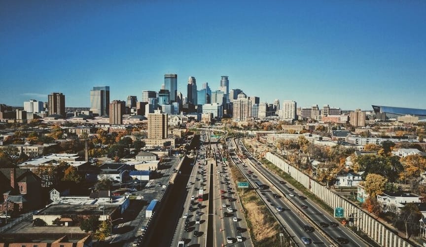 an aerial view of a large city with a highway in the foreground and skyscrapers in the background
