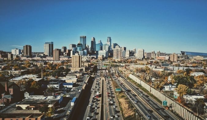 an aerial view of a large city with a highway in the foreground and skyscrapers in the background