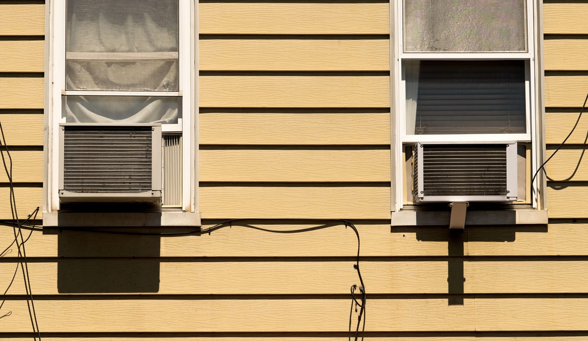 Two window air conditioner units in a yellow house