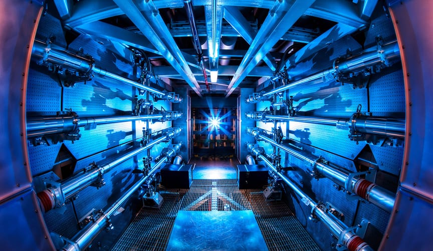 A long, narrow room with metallic tubes running the length of the walls, illuminated by blue light.