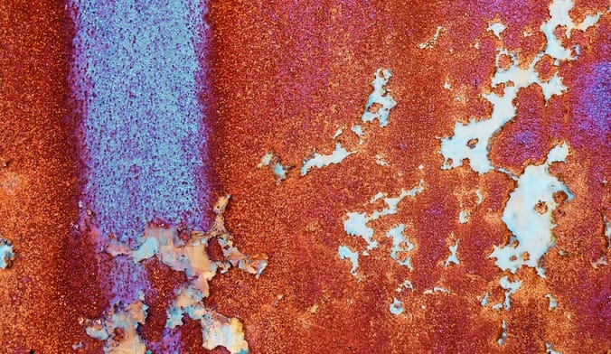 A rusty metal surface that is dark red and blue