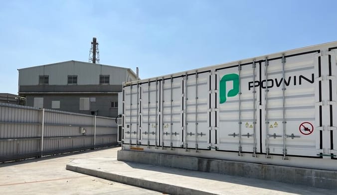 A large white rectangular metal structure with the word POWIN printed on it. It is situated on a concrete pad.