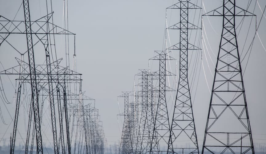 Two long parallel rows of transmission lines and towers in California