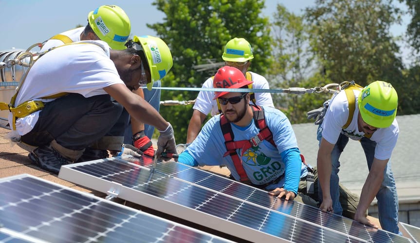 Workers install solar panels on a rooftop