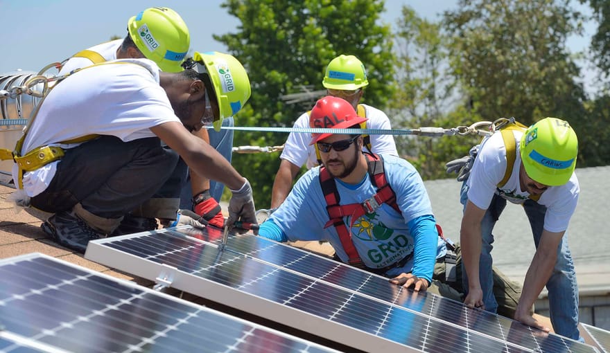 Workers install solar panels on a rooftop