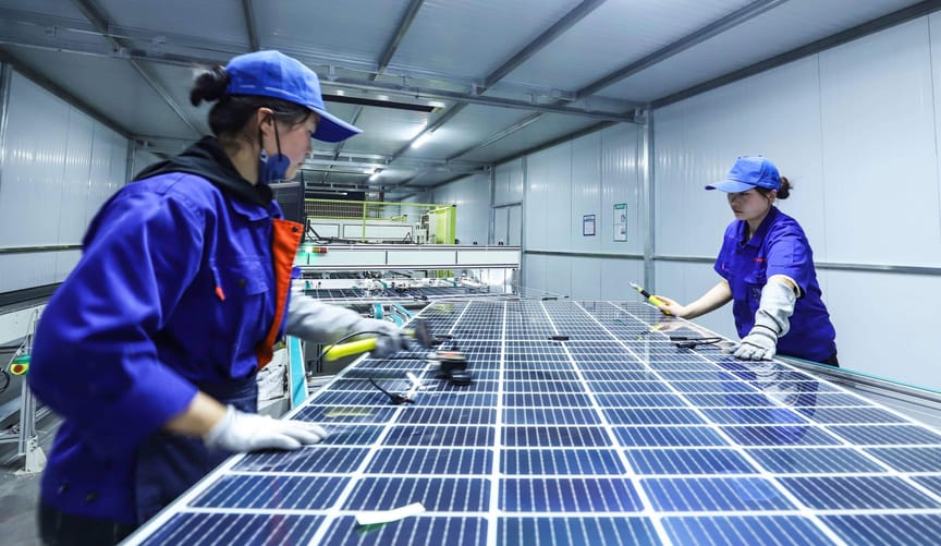 Workers inspect photovoltaic modules at a production line