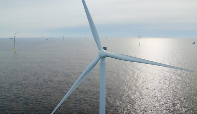 A dozen white wind turbines in the ocean