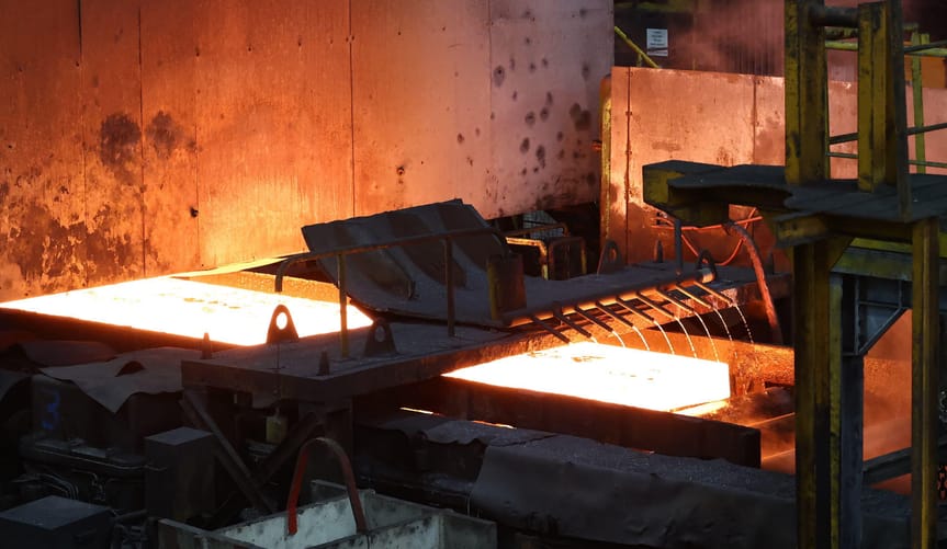 A steel slab passes on a hot mill train during the manufacture of the steel