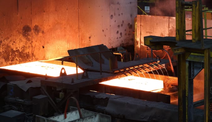 A steel slab passes on a hot mill train during the manufacture of the steel