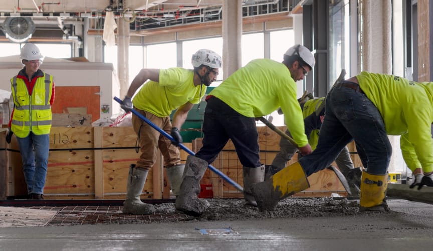 Workers smooth out concrete made from startup Sublime Systems' low-carbon cement at a construction site in Boston