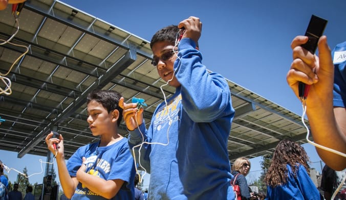Students at a school in Merced, California use handheld solar sensors to check power output from a carport solar canopy