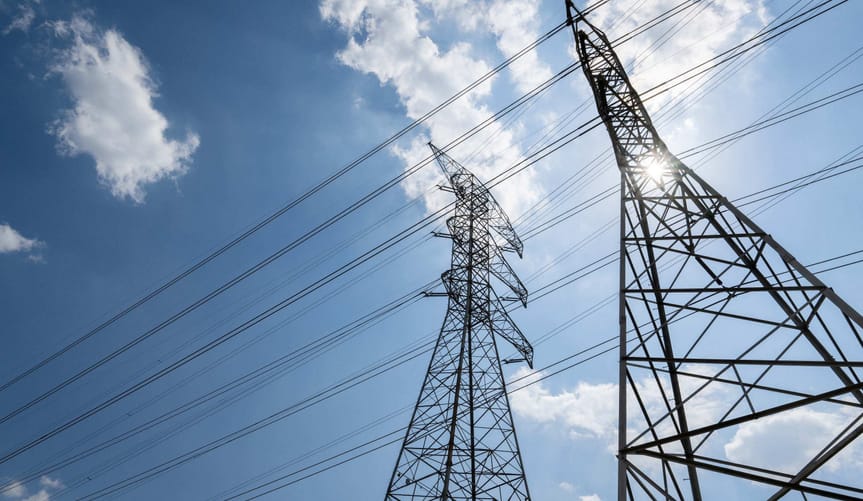 Transmission towers seen from below against a blue sky