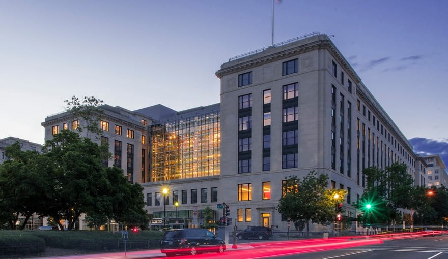 Large corner building at dusk with American flag flying from roof.