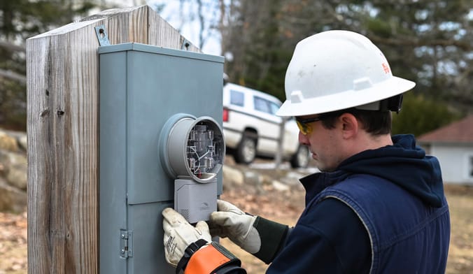 Utility worker installing meter attachment device to electric meter