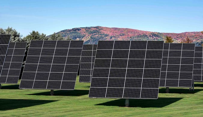 A solar panel array against a hill in the fall.
