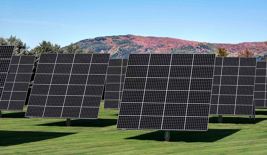 A solar panel array against a hill in the fall.
