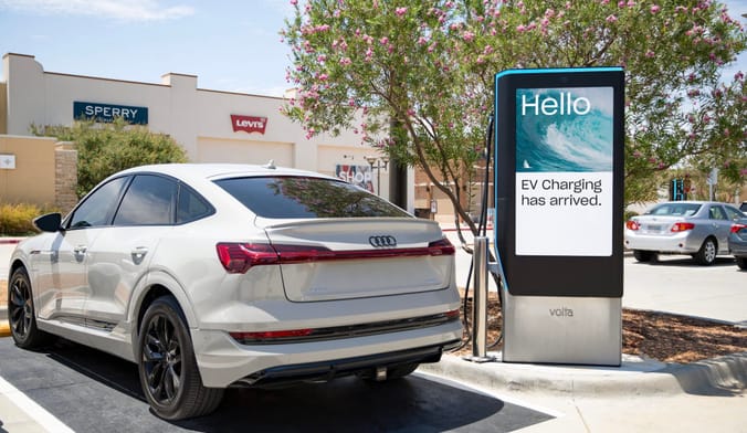 A Volta EV charger with video advertising screen in a parking lot in Dallas