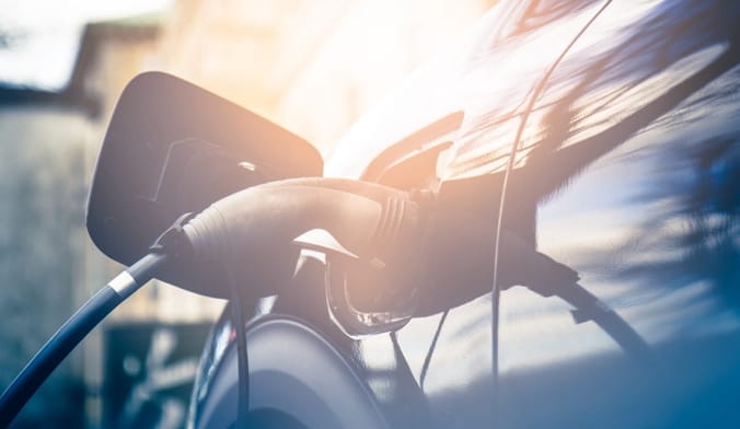 An electric vehicle plugged into a charging cord in front of a home