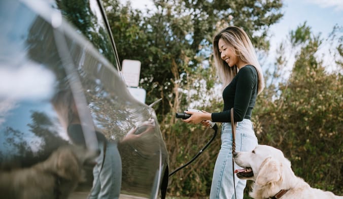 EV owner with dog plugging in a charging cord