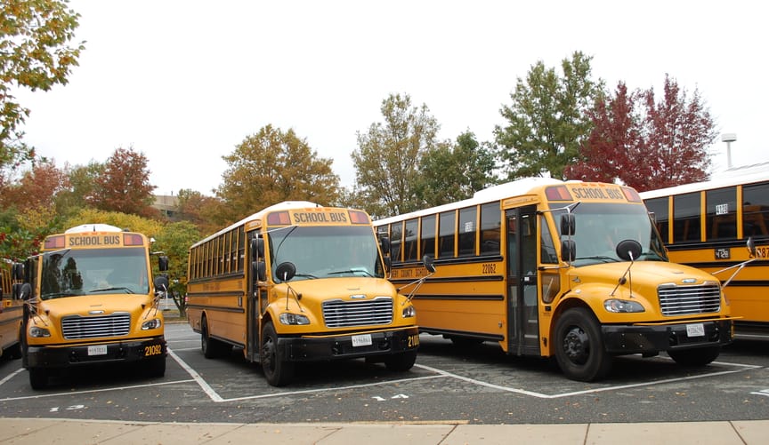 Electric school buses parked in a school parking lot